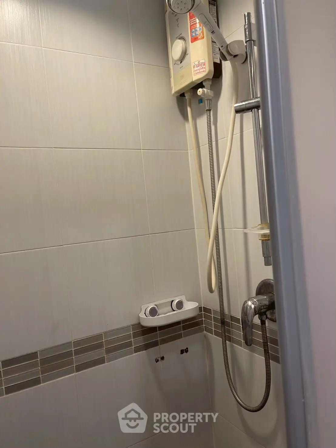 Compact bathroom shower area with modern fixtures and water heater.