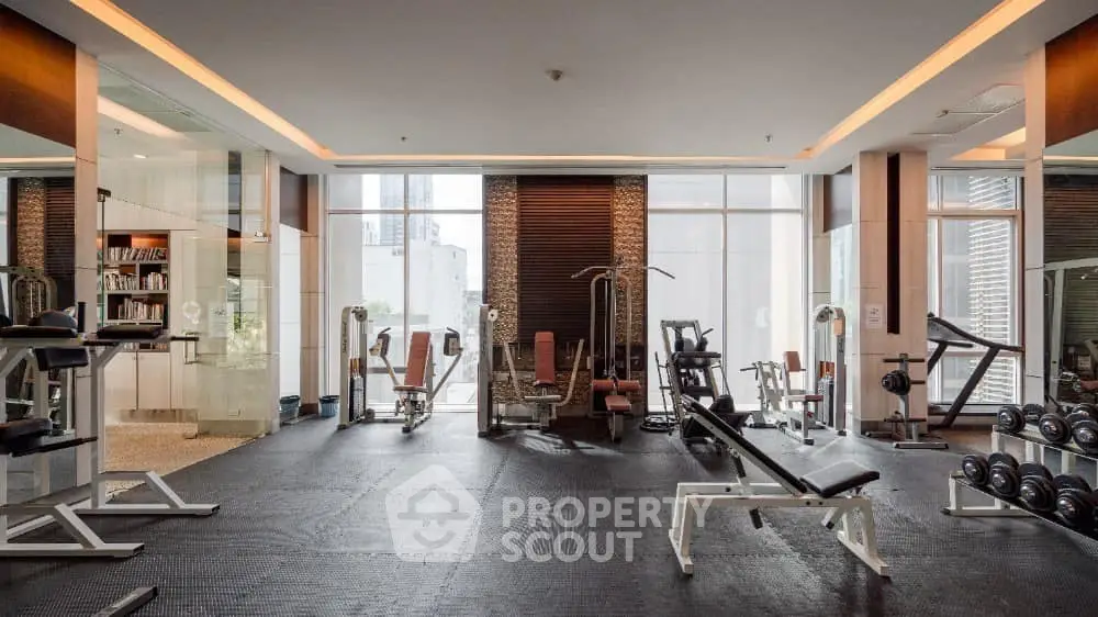 Spacious modern gym with state-of-the-art fitness equipment and large windows for natural light.