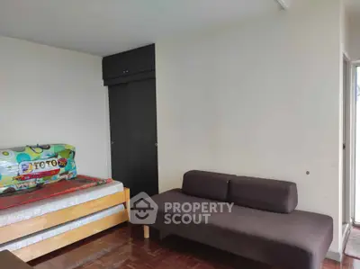 Spacious bedroom with wooden flooring and modern furniture in a cozy apartment.