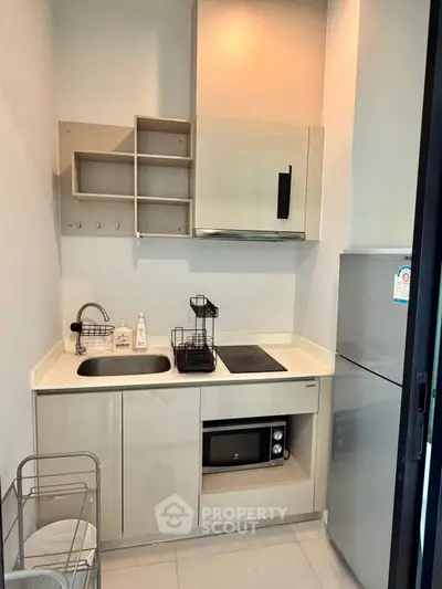 Compact modern kitchen with sleek cabinetry and built-in appliances in a cozy apartment.