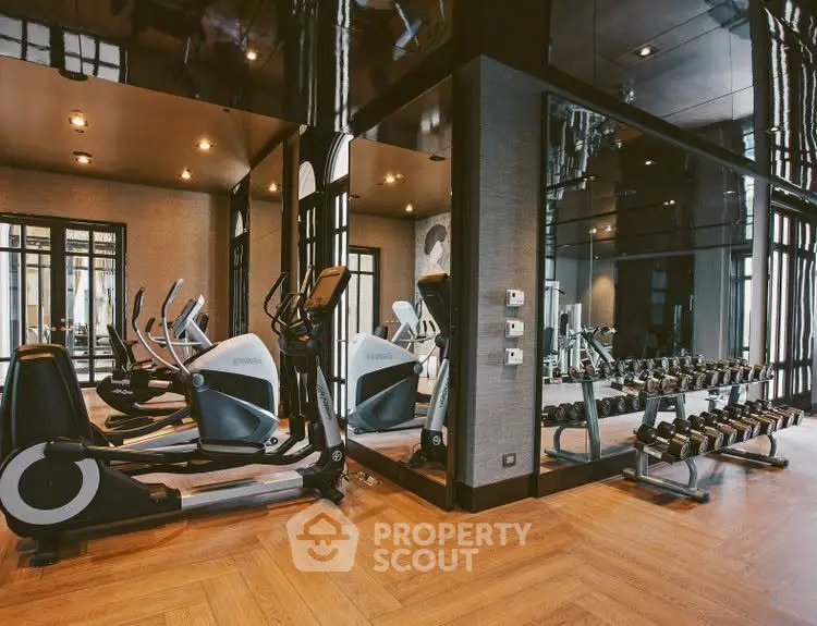 Luxurious gym with modern equipment and elegant wooden flooring in upscale residential building.
