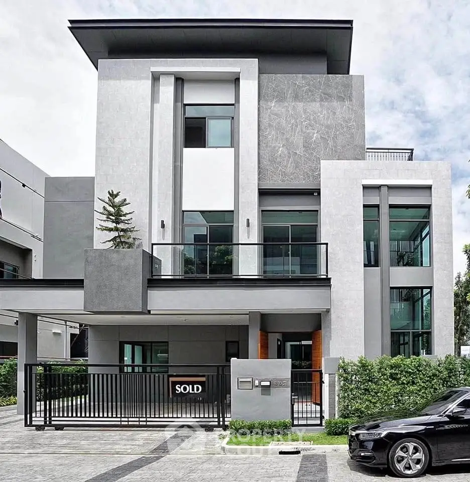 Modern luxury home with sleek design and sold sign, featuring large windows and a stylish facade.