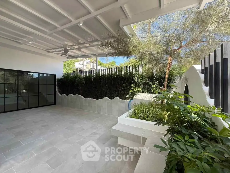 Modern outdoor patio with sleek design and lush greenery, perfect for relaxation and entertainment.