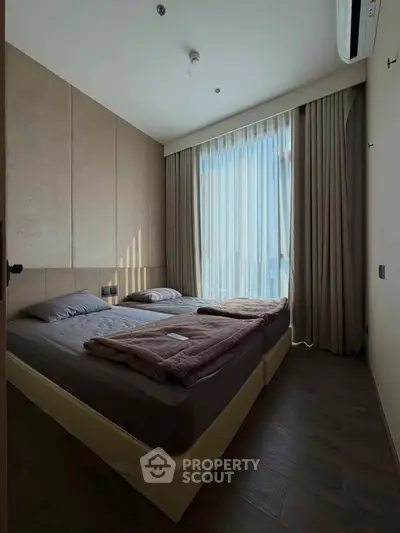 Cozy bedroom with large window and modern decor, perfect for relaxation and comfort.