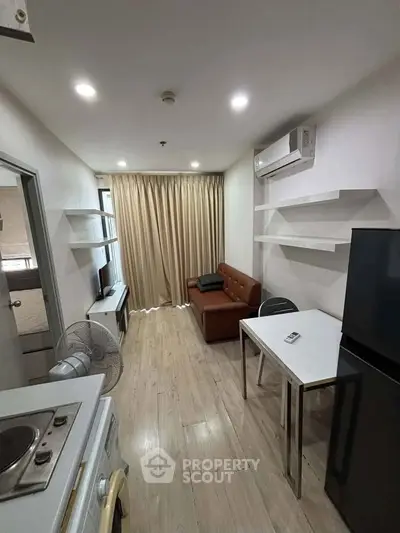 Modern compact living room with sleek furniture and open layout, featuring air conditioning and stylish shelving.