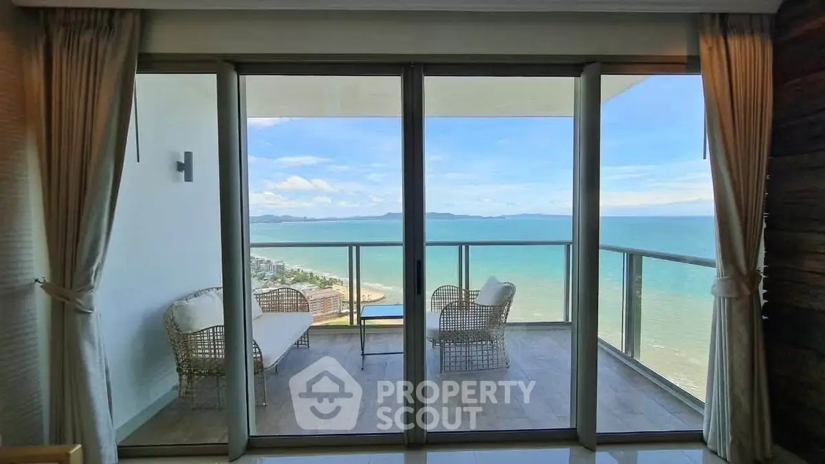 Stunning ocean view from modern balcony with glass doors and elegant seating.