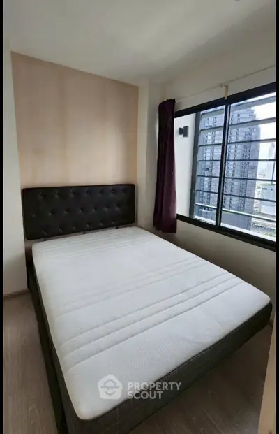 Cozy bedroom with large window offering city views, featuring a comfortable bed and modern decor.