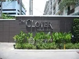 Modern building entrance with lush greenery at The Clover, showcasing urban living.