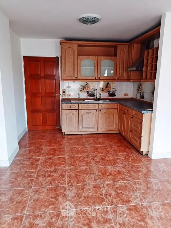 Charming kitchen with wooden cabinets and tiled floor, perfect for culinary enthusiasts.