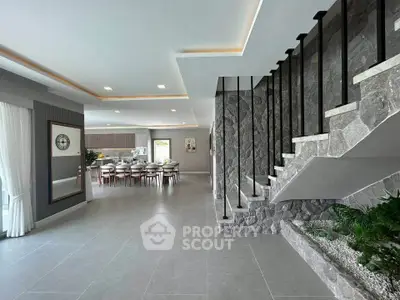 Luxurious open-plan living area with modern staircase and elegant dining space.
