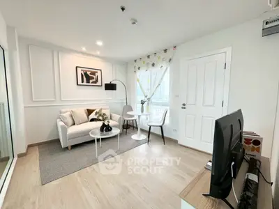 Modern living room with stylish decor and natural light, featuring a cozy seating area and sleek TV setup.