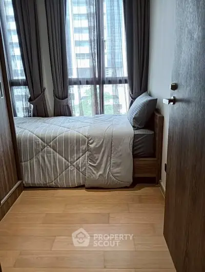 Cozy bedroom with modern decor and large windows offering natural light.