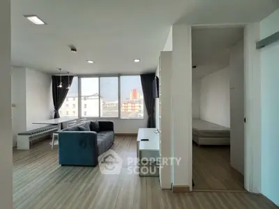 Spacious modern living room with large windows and city view, featuring a cozy sofa and dining area.