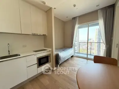 Modern studio apartment with kitchenette and city view balcony, perfect for urban living.