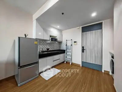 Modern kitchen with sleek appliances and wooden flooring in a stylish apartment.