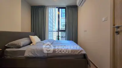 Modern bedroom with large window and stylish decor in a high-rise apartment.