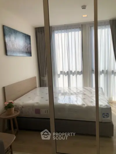 Modern bedroom with large windows and stylish decor in a contemporary apartment.