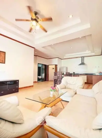 Spacious living room with modern open kitchen and ceiling fan, perfect for family gatherings.