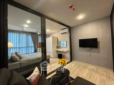 Modern apartment interior with cozy living room and stylish bedroom separated by glass wall.