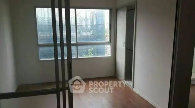 Spacious room with large window and wooden flooring, ideal for customization.