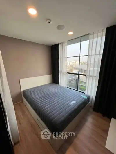 Modern bedroom with large window and stylish decor in a contemporary apartment.