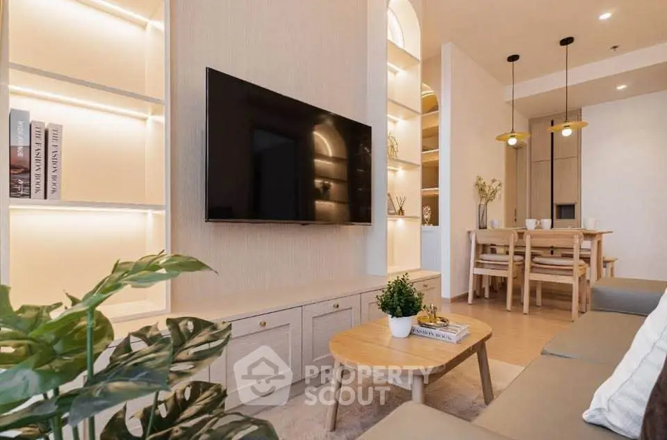 Modern living room with sleek TV setup and elegant dining area, featuring stylish lighting and cozy decor.