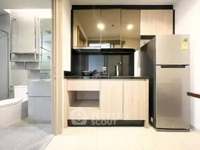 Modern compact kitchen with stainless steel fridge and sleek cabinetry