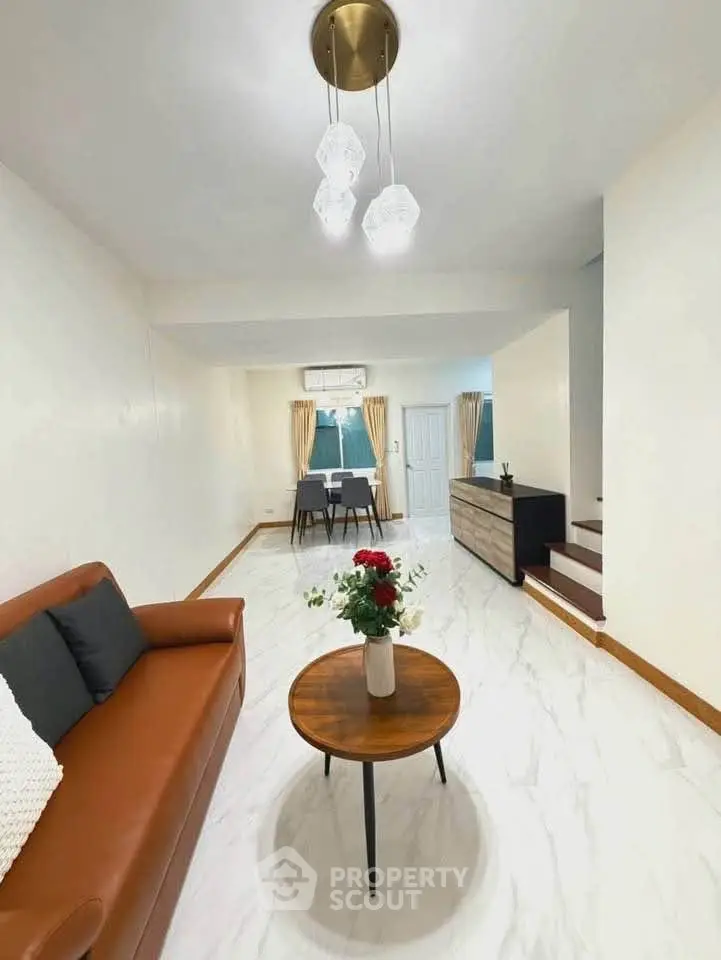 Spacious living room with modern decor and elegant lighting, featuring a cozy sofa and stylish coffee table.