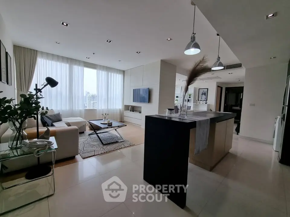 Spacious modern living room with open kitchen and large windows offering city views.