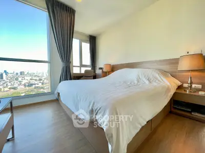 Spacious bedroom with city view, featuring modern furniture and large windows for natural light.