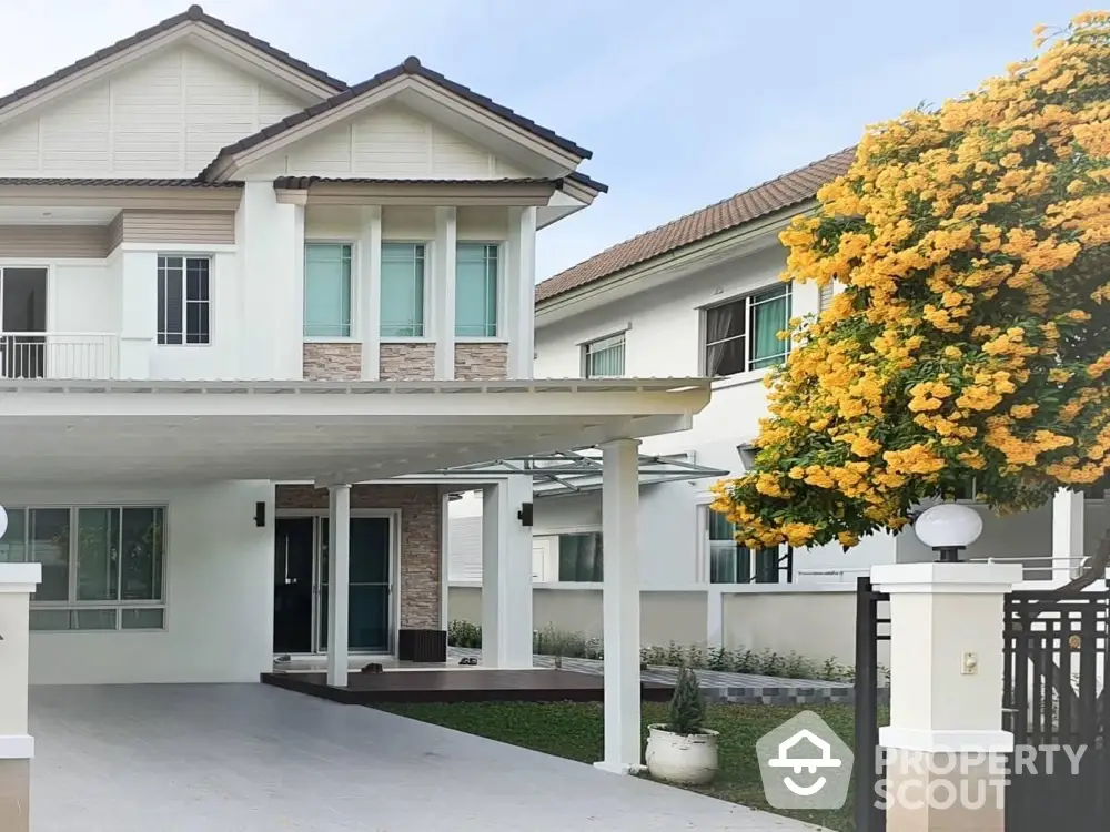 Charming two-story house with spacious driveway and vibrant flowering tree