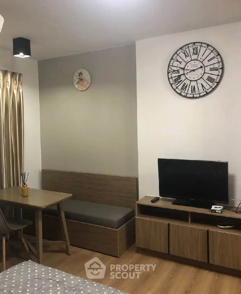 Cozy living room with modern decor, featuring a wall clock, TV, and stylish furniture.