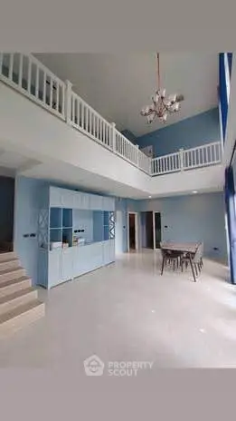 Spacious modern living room with high ceilings and elegant chandelier in a duplex apartment.