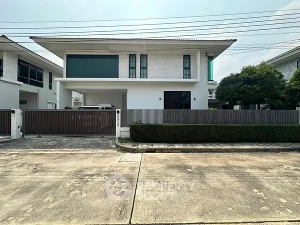 Modern two-story house with sleek design and spacious driveway in suburban neighborhood.