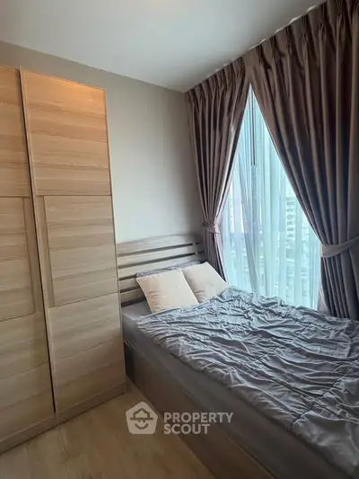 Cozy bedroom with modern wooden furniture and large window with city view.