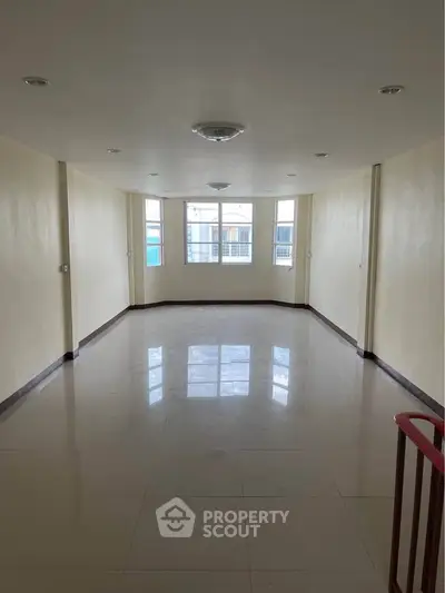 Spacious empty room with large window and glossy tiled floor, perfect for customization.