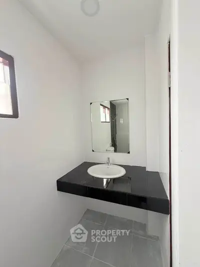 Modern minimalist bathroom with sleek black countertop and mirror.