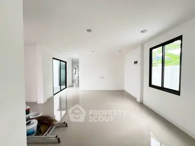 Spacious modern living room with large windows and glossy tiled floors in a minimalist design.