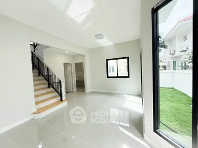 Bright and spacious modern living room with large windows and staircase in a contemporary home.