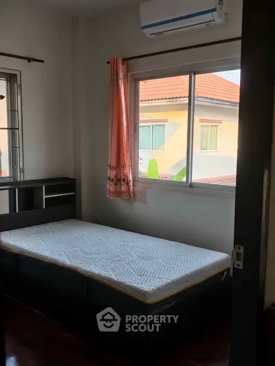 Cozy bedroom with natural light and air conditioning, perfect for relaxation.