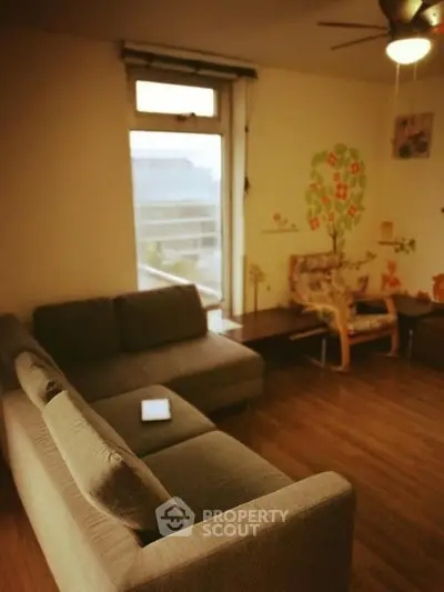 Cozy living room with modern sofa and artistic wall decor, featuring a large window for natural light.