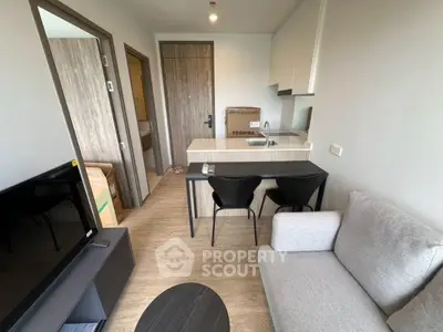 Modern compact living room with kitchen in a cozy apartment, featuring sleek furniture and a minimalist design.