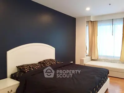 Spacious bedroom with elegant dark accent wall and natural light