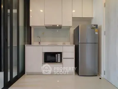 Modern kitchen with sleek white cabinets and stainless steel appliances in a compact layout.