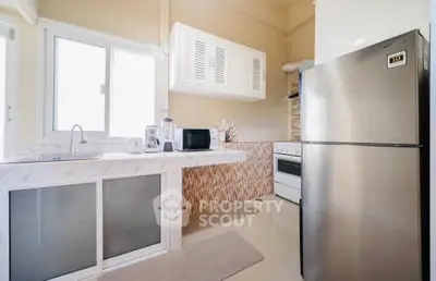 Modern kitchen with stainless steel fridge and sleek countertops in a bright, airy space.