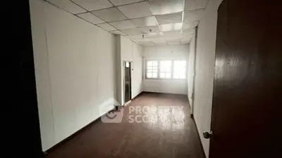 Spacious empty room with wooden flooring and large window, ideal for customization.