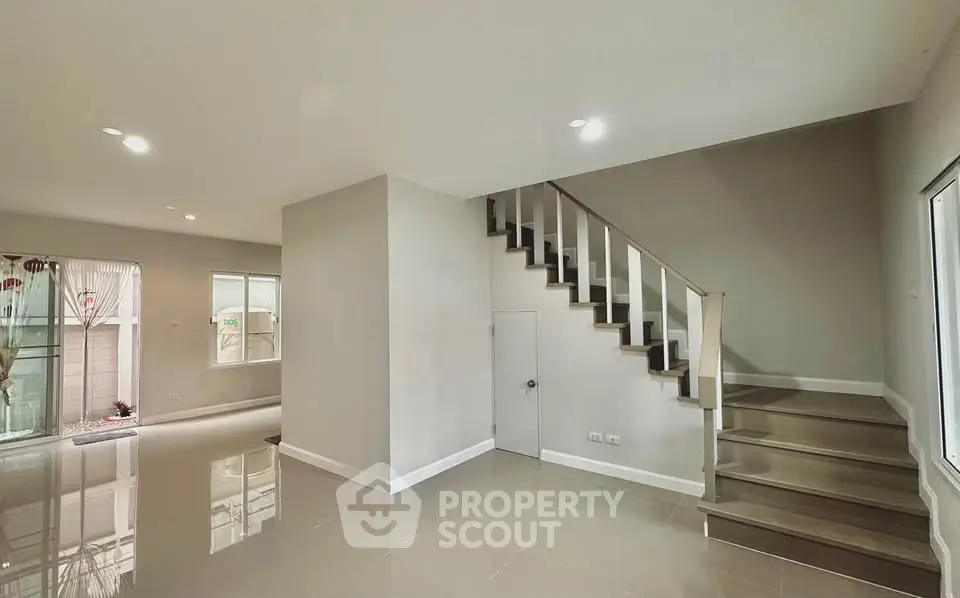 Modern interior with sleek staircase and glossy tile flooring in a spacious living area.