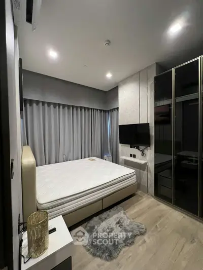 Modern bedroom with sleek design, featuring a large bed, wall-mounted TV, and stylish wardrobe.