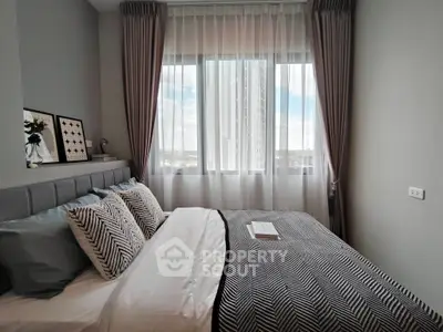 Cozy bedroom with stylish decor and large window offering natural light.