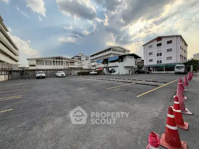 Spacious parking lot with multiple parking spaces in a residential area under a cloudy sky.